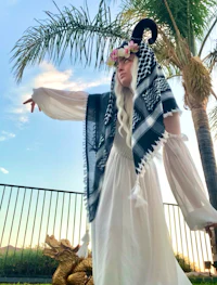a woman in a white and black dress posing in front of a palm tree