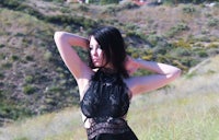 a woman in a black lace dress posing in a field