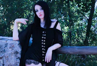 a woman in a black dress posing on a rock