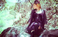 a woman in a black dress sitting on a rock