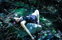 a woman laying on a rock in the woods