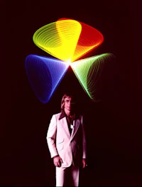 a man in a suit standing in front of a colorful light sculpture